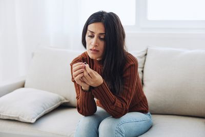 Young woman using phone while lying on sofa at home