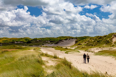 Rear view of people walking on beach