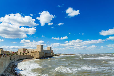 Buildings on beach against cloudy sky