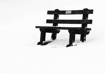 Empty bench on snow covered field during winter