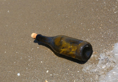 High angle view of beer bottle on sand at beach