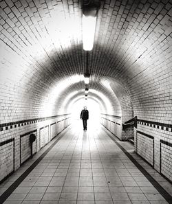 Rear view of woman walking in tunnel