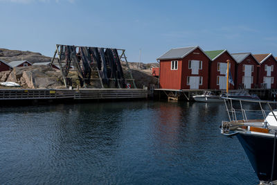 Sailboats moored on sea by houses against sky