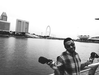 Full length of man sitting on riverbank against clear sky