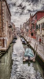 View of canal and buildings against cloudy sky