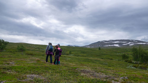 Rear view of people walking on mountain against sky