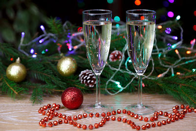 Close-up of champagne flutes by christmas decoration on table