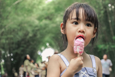 Portrait of cute girl eating ice cream against trees