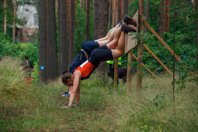 Side view of teenage girl holding plant in forest