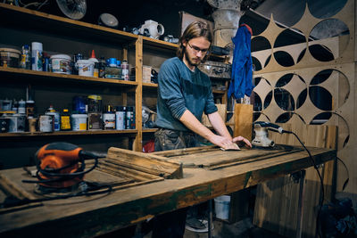 Carpenter sands wooden door with sandpaper and sanding machine