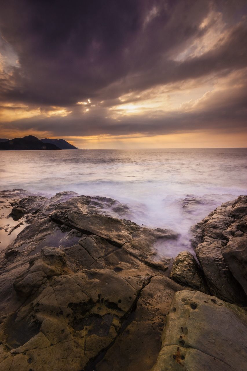 sea, water, horizon over water, scenics, sky, sunset, beauty in nature, tranquil scene, tranquility, beach, cloud - sky, nature, rock - object, shore, idyllic, wave, cloudy, dramatic sky, orange color, cloud