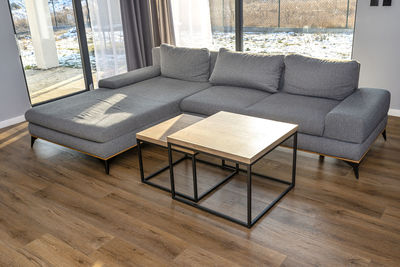 A modern and simple living room in the house with a gray sofa,  two tables one below the other.