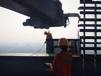 Rear view of man working on highrise building