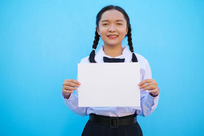 Portrait of a smiling girl standing against blue background