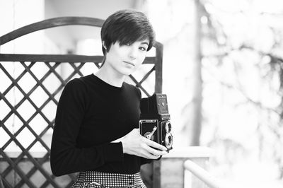 Young woman using phone while standing on mirror