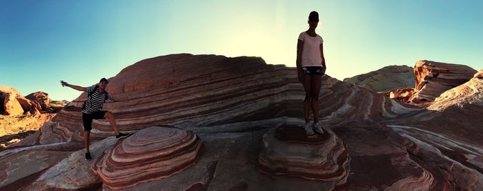 Rear view of man standing on cliff against sky