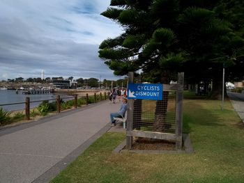 Information sign by trees in city against sky