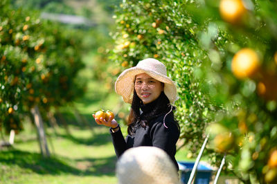 Portrait of young woman wearing hat against trees