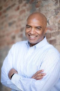 Portrait of smiling man with arms crossed against brick wall