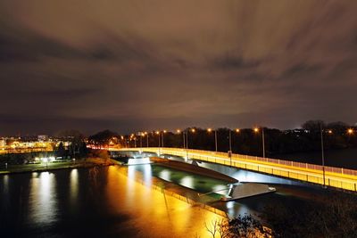 Illuminated bridge over river against sky in city at night