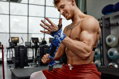 Rear view of shirtless man exercising in gym