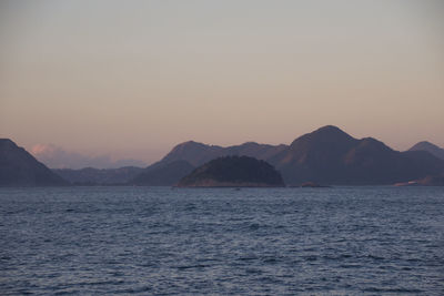 Scenic view of sea and mountains against clear sky