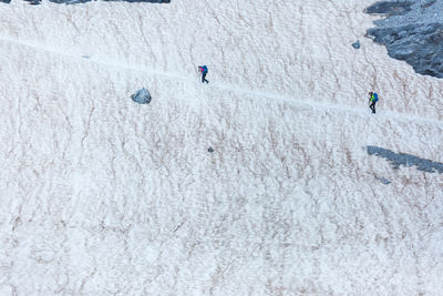 Alpinists walking on path on glacier while exploring pyrenees mountains on sunny day