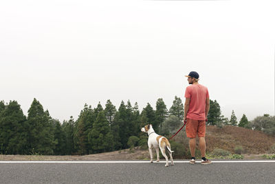 Man standing with dog by road