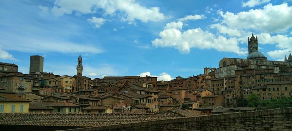 Panoramic view of buildings against cloudy sky