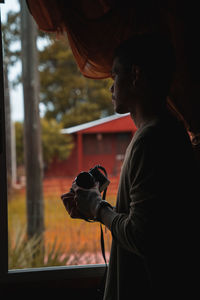 Rear view of man photographing through window