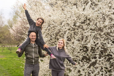 Family having fun with flowering tree in blooming spring garden