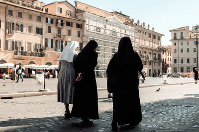 Rear view of people walking on street in city