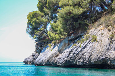 Scenic view of rocks by sea against sky