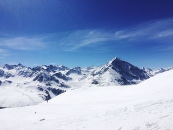 Snow covered landscape against blue sky