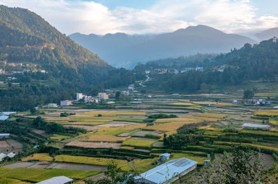 Scenic view of agricultural field by mountains against sky