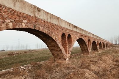 Arch bridge on field against clear sky