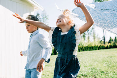 Girl and boy running through the washing on the line with great joy