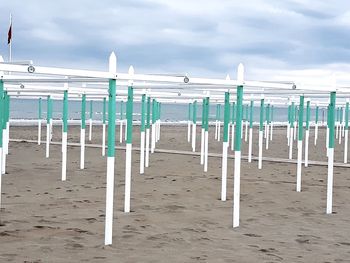 Deck chairs on beach against sky