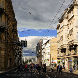 People walking in city street amidst buildings against sky
