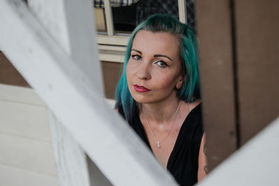 Portrait of young woman with dyed hair seen from window