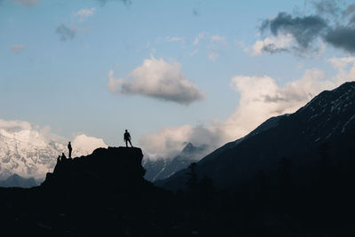 Silhouette people standing on mountain against sky