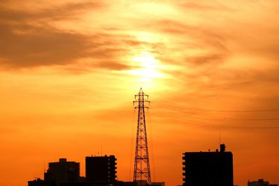 Low angle view of electric pylon against sky at sunset