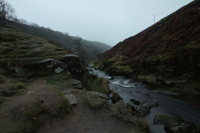 Scenic view of stream by mountains against sky