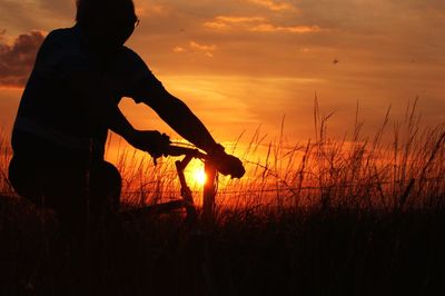 Silhouette people on field at sunset