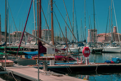 Sailboats moored at harbor against clear blue sky