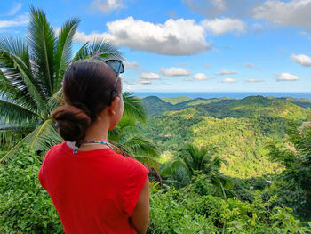 Rear view of young woman standing against sky