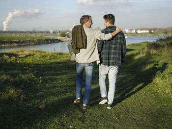 Father arm around son walking at riverbank