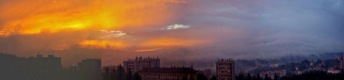 Panoramic view of buildings against dramatic sky during sunset