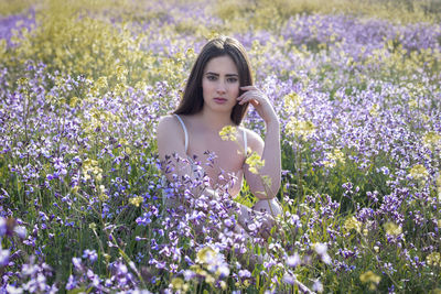 Portrait of woman with purple flowers in field