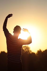 Silhouette man standing against orange sky